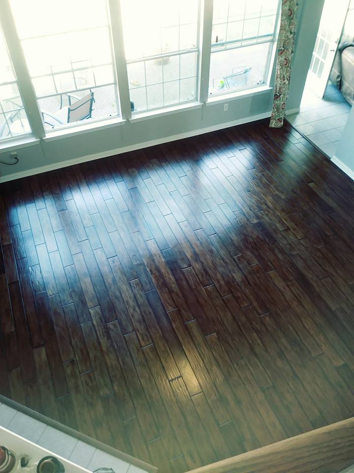 A dark wood floor with sunlight coming through the window.