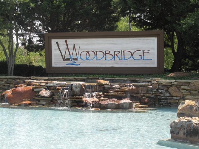 A sign that says woodbridge with water flowing into it.