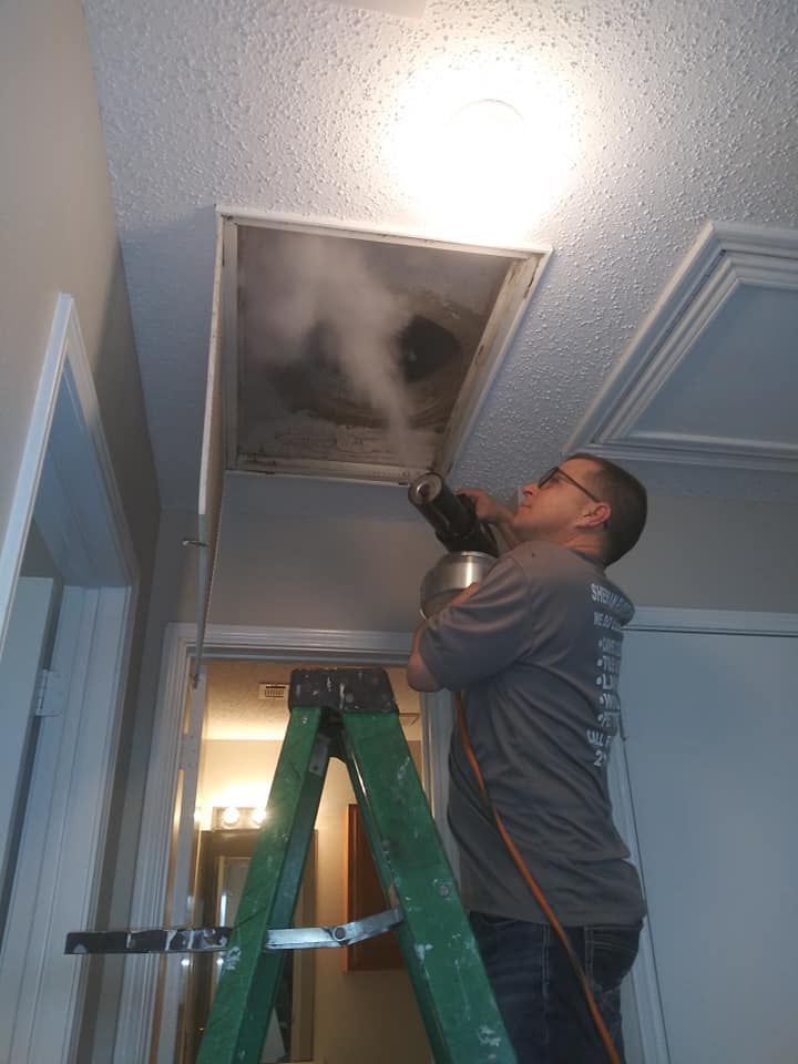 A man on ladder looking at the ceiling