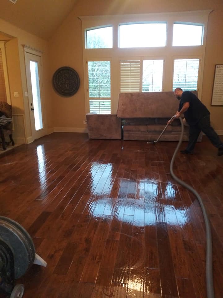 A man cleaning the floor of a living room.
