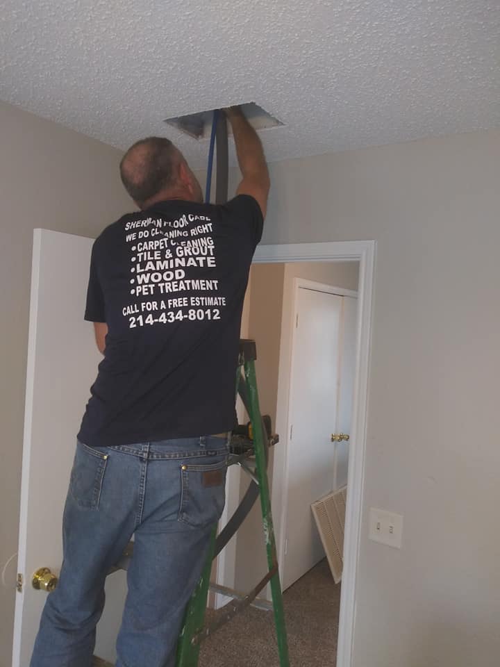 A man on a ladder fixing the ceiling.