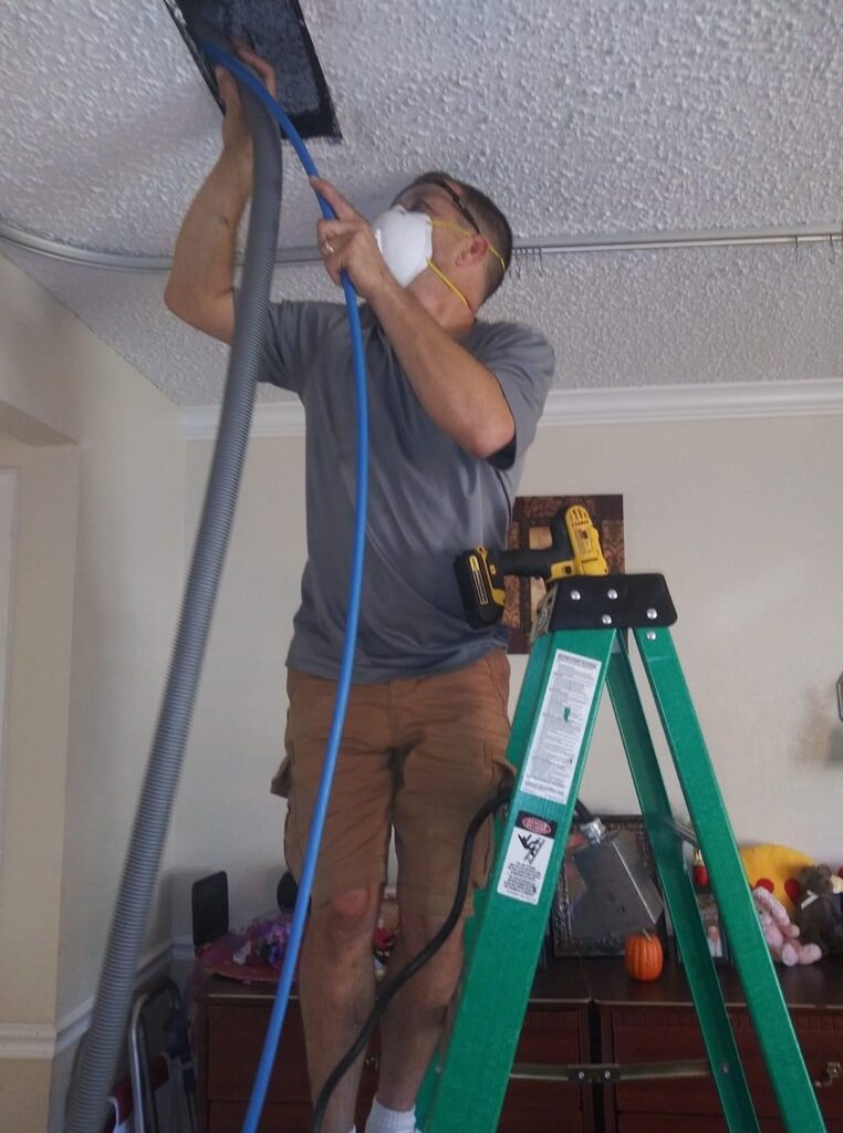 A man is hanging up the lights on the ceiling