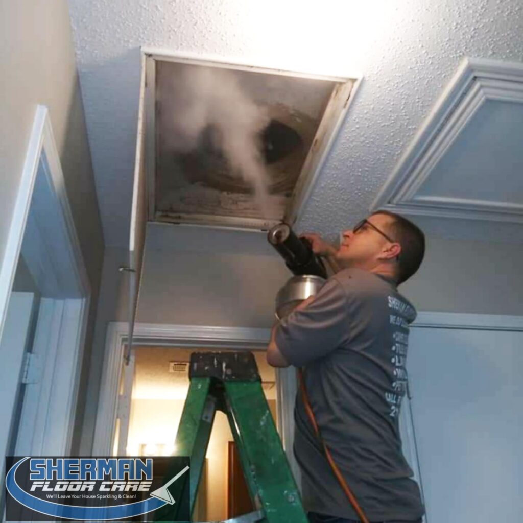 A man on a ladder in front of a ceiling vent.