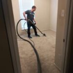 A man is vacuuming the floor in his home.