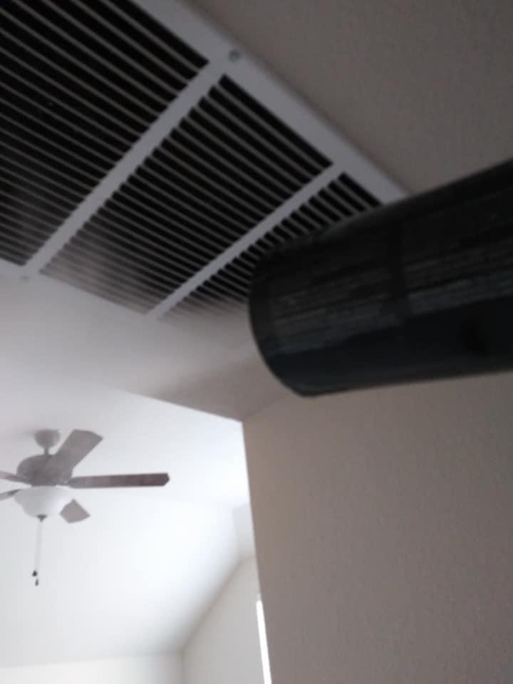 A ceiling fan in the middle of an air vent.