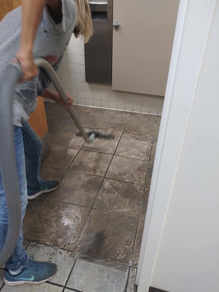 A person cleaning the floor with a vacuum cleaner.