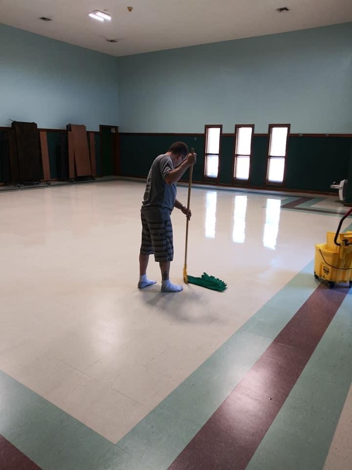 A man is cleaning the floor with a mop.