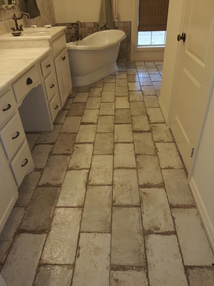 A bathroom with tile floor and white cabinets