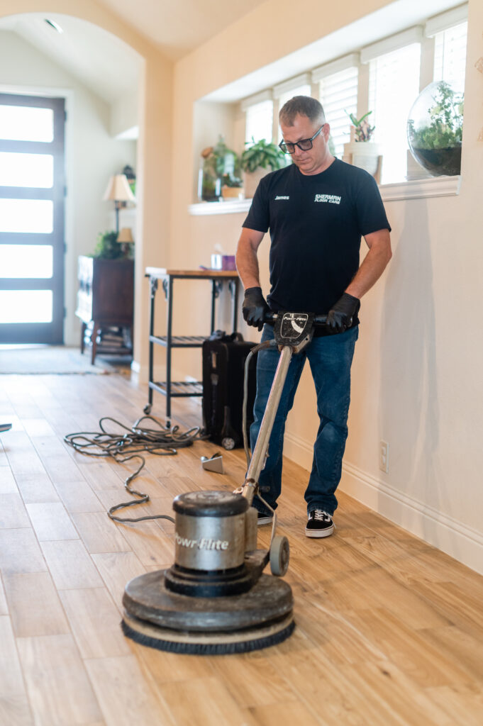 A man is cleaning the floor with an electric sander.