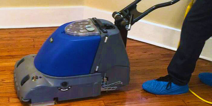 A person is using an electric floor scrubber.